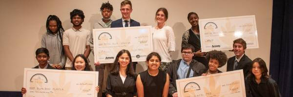 Group of students showcasing 4 large checks from a competition, representing CEI